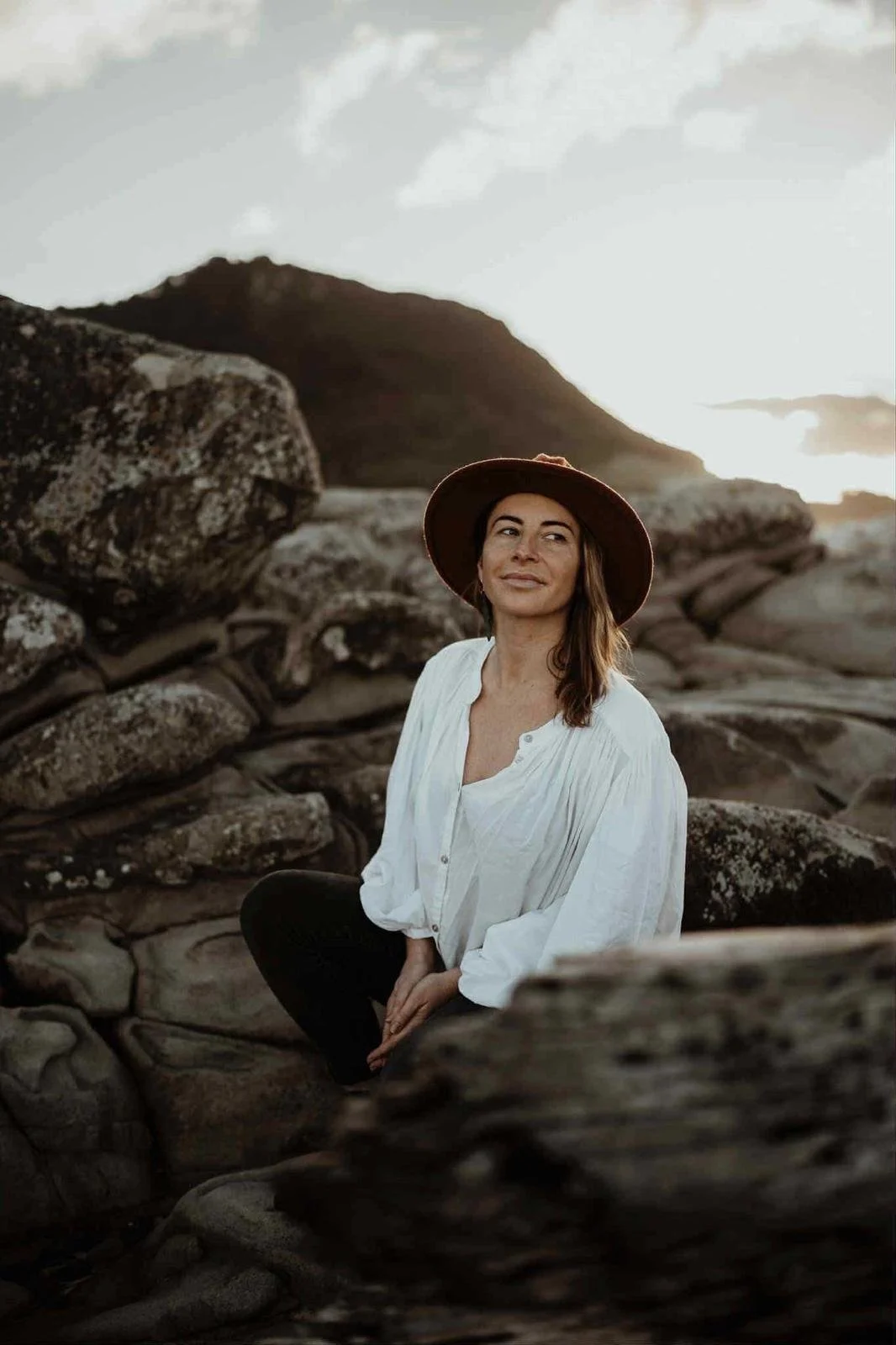 Chloe Rigg, counsellor, seated on coastal rocks